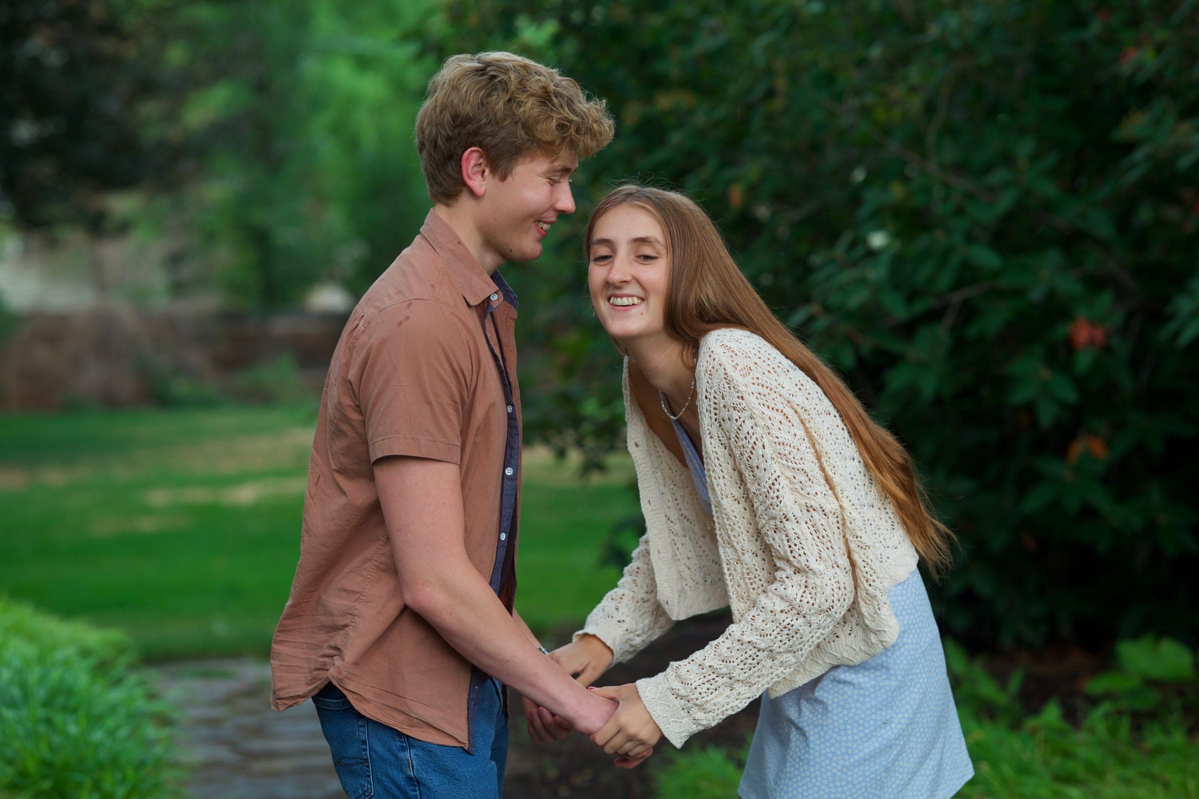 Molly laughing as she and Tyler hold hands on a garden path
