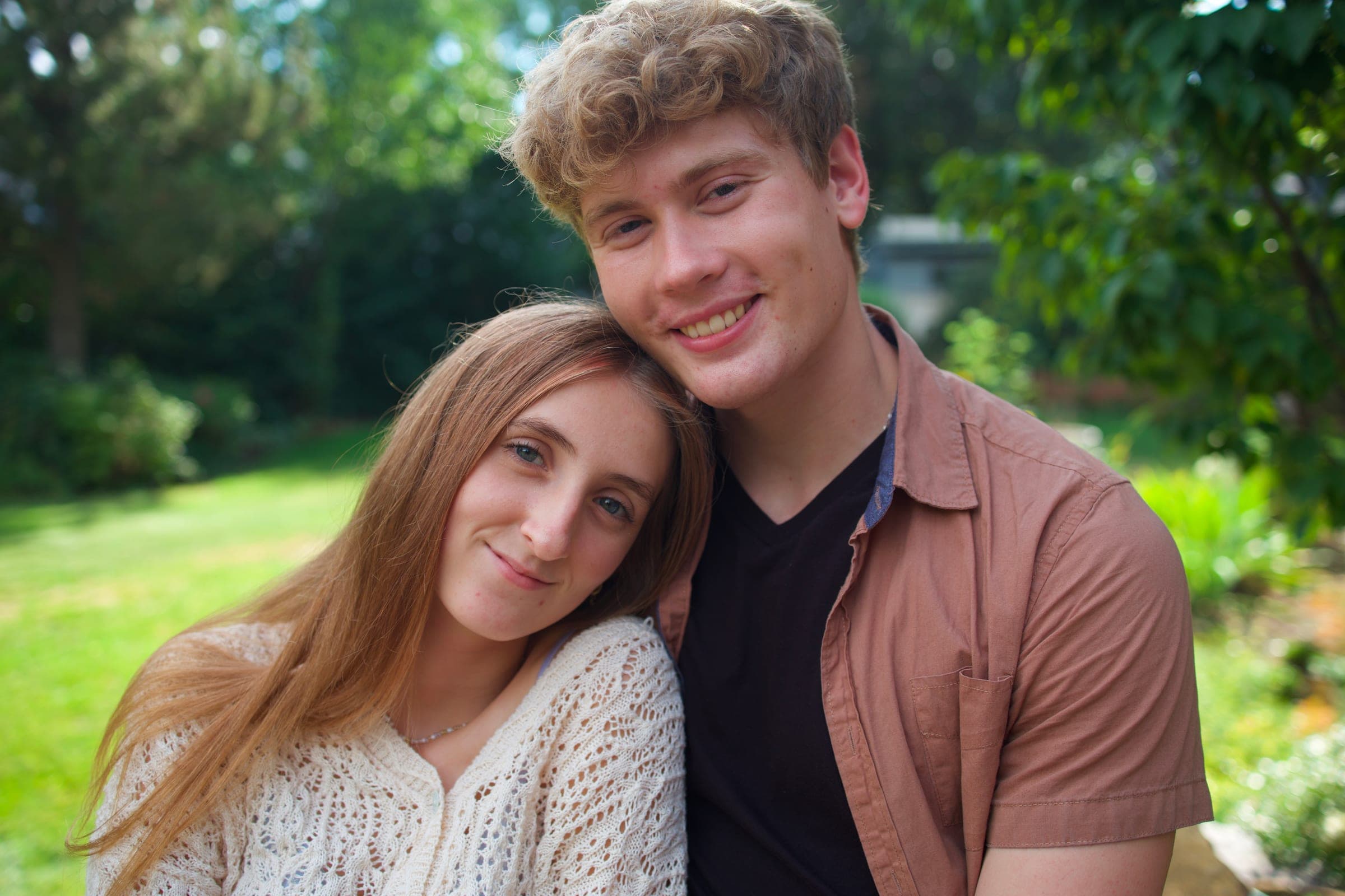 Molly leaning on Tyler's shoulder on a sunny lawn